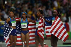 Four athletes with American flags draped around their shoulders