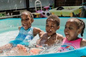 Three children splashing in a pool
