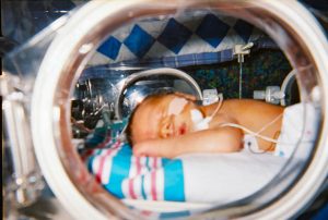 An infant is in an incubator in a neonatal intensive care unit